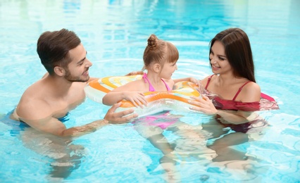Photo of Happy family with inflatable ring in swimming pool
