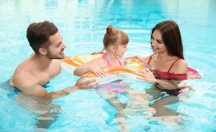 Happy family with inflatable ring in swimming pool