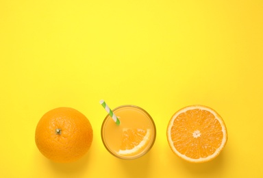 Photo of Glass of orange juice and fresh fruits on yellow background, flat lay. Space for text