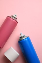 Cans of different graffiti spray paints on pink background, flat lay