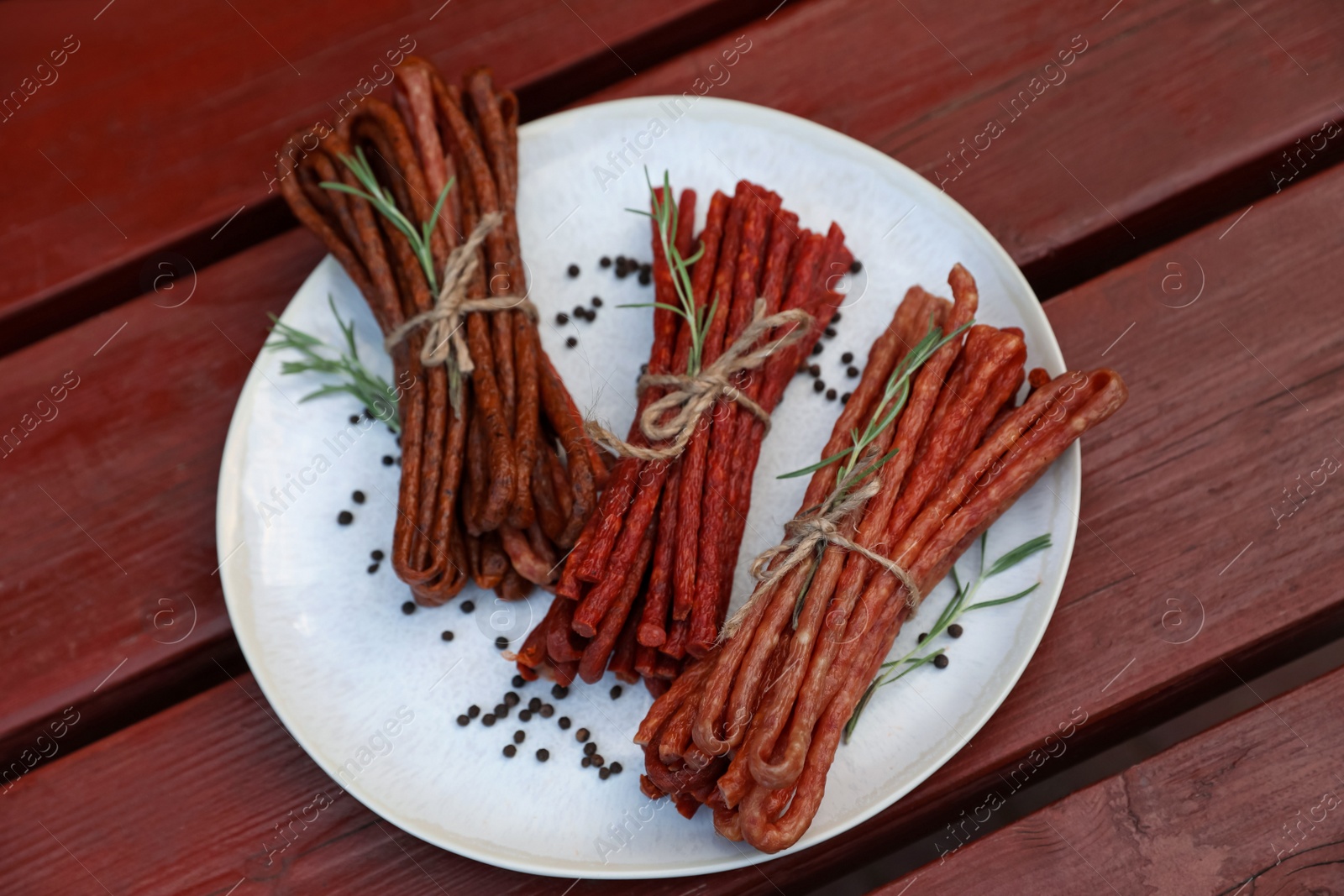 Photo of Tasty dry cured sausages (kabanosy) and spices on wooden table, top view