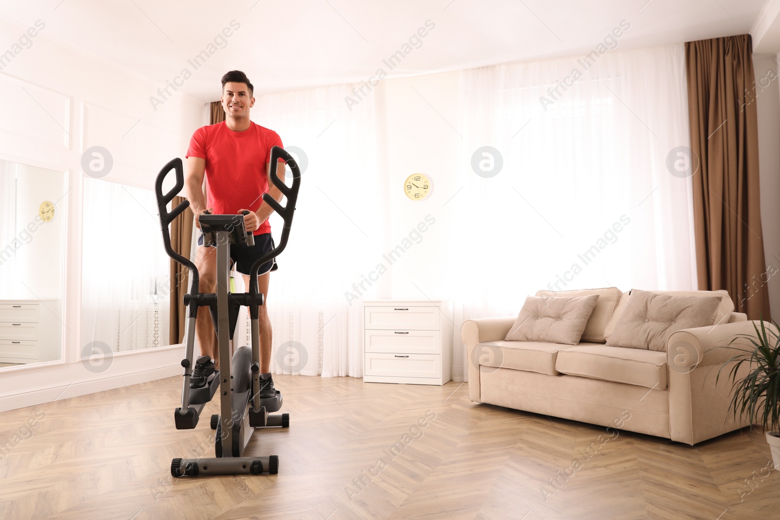 Photo of Man using modern elliptical machine at home