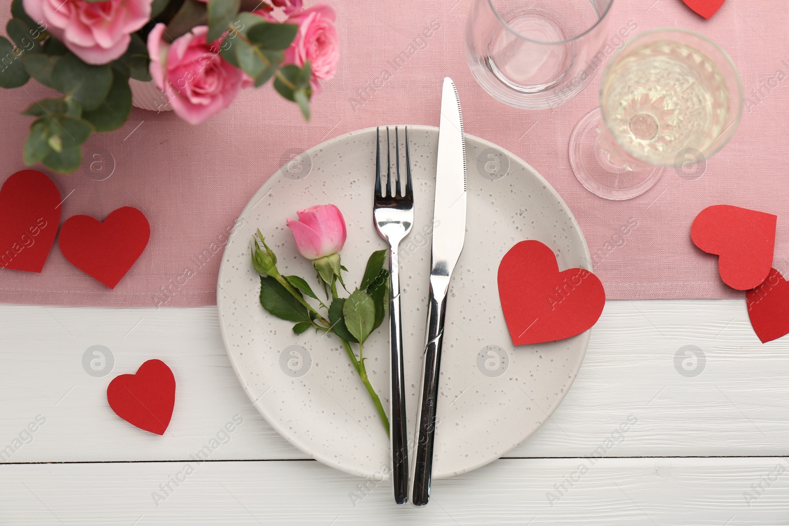 Photo of Romantic place setting with flowers and red paper hearts on white wooden table, flat lay. St. Valentine's day dinner