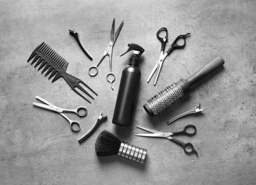 Flat lay composition with scissors and other hairdresser's accessories on grey background