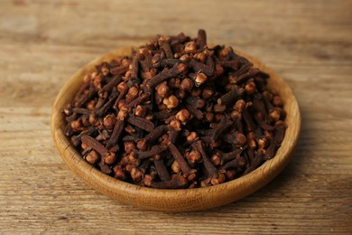 Plate of aromatic dry cloves on wooden table
