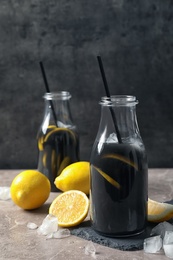 Photo of Bottles with natural black lemonade on table