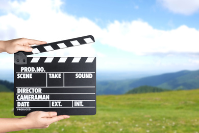 Assistant holding clapperboard outdoors, closeup. Cinema production 