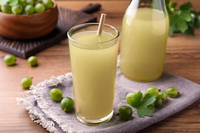 Tasty gooseberry juice in glass on wooden table