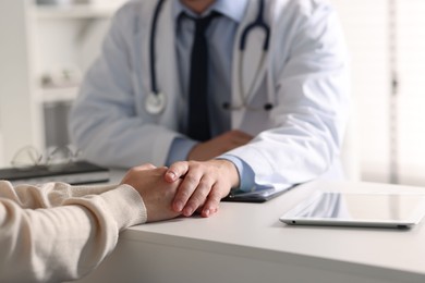 Professional doctor working with patient at white table in hospital, closeup