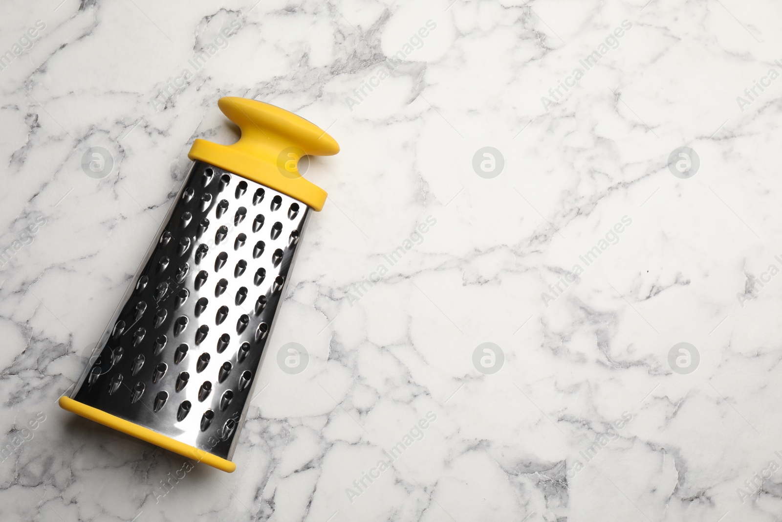 Photo of Modern grater on white marble table, top view. Space for text