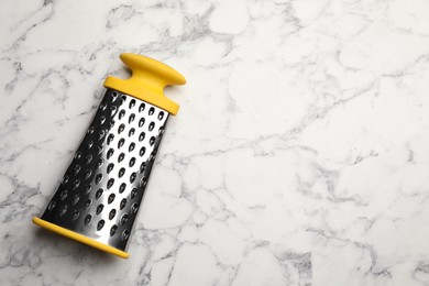 Photo of Modern grater on white marble table, top view. Space for text