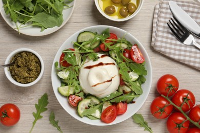 Photo of Delicious burrata salad served on wooden table, flat lay