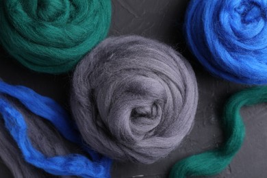 Photo of Colorful felting wool on dark textured table, flat lay