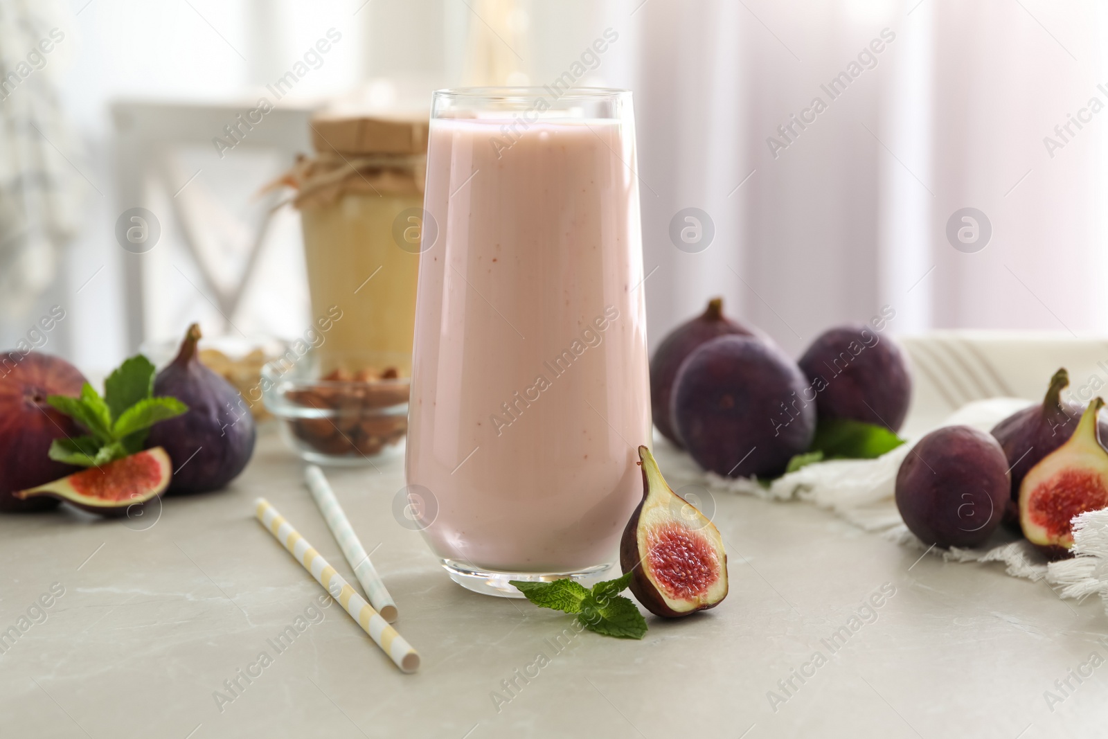 Photo of Delicious fig smoothie in glass on light table