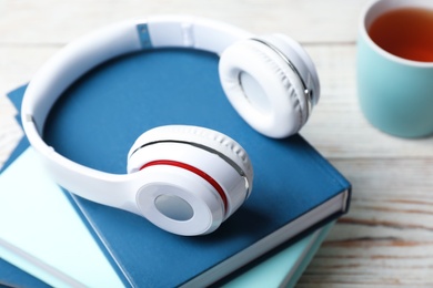 Modern headphones with hardcover books on wooden table, closeup