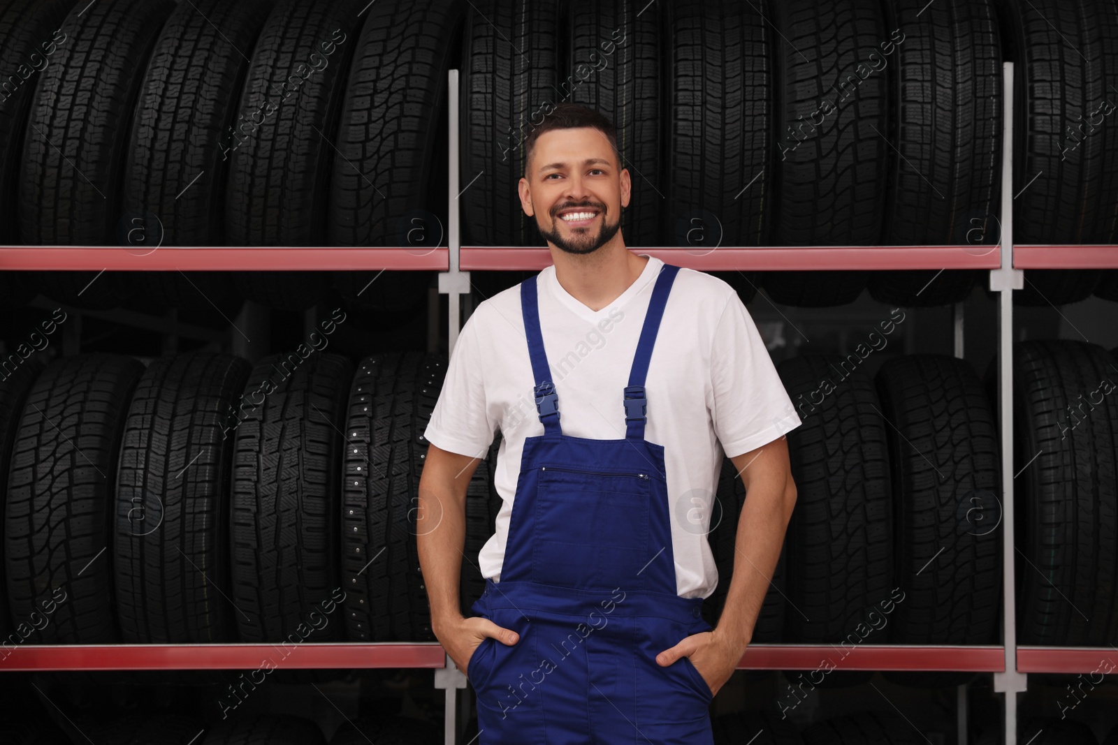 Photo of Male mechanic near rack with car tires in auto store