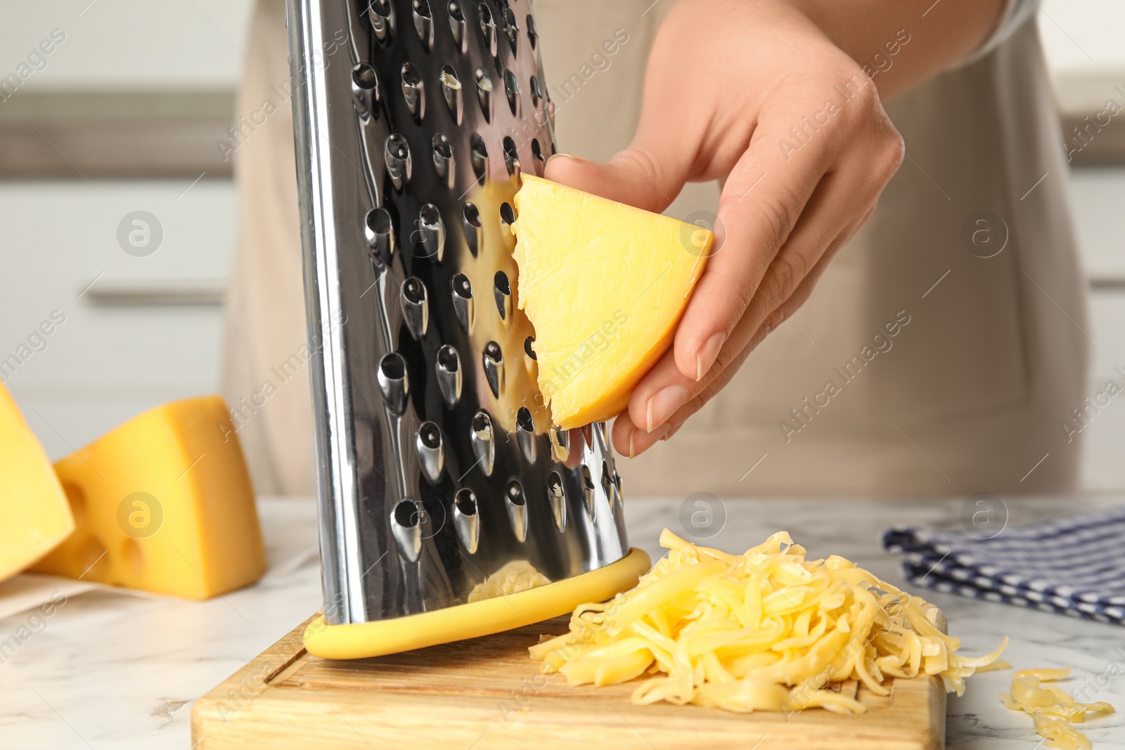 Photo of Woman grating fresh cheese at table, closeup