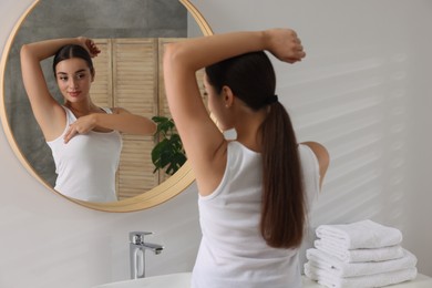 Photo of Beautiful young woman doing breast self-examination near mirror in bathroom