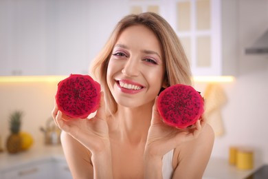Young woman with fresh pitahaya in kitchen. Exotic fruits