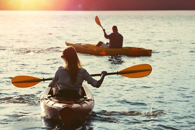 Photo of Couple kayaking on river in evening, back view. Summer activity