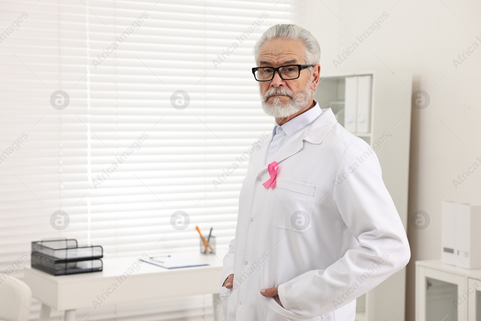 Photo of Mammologist with pink ribbon in hospital, space for text. Breast cancer awareness