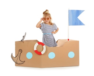 Photo of Cute little girl playing with cardboard ship on white background