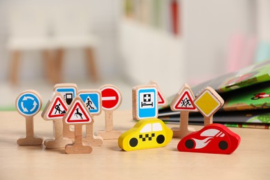 Photo of Set of wooden road signs and cars on table indoors, closeup. Children's toys