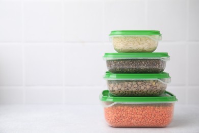 Photo of Plastic containers filled with food products on white table near tiled wall. Space for text