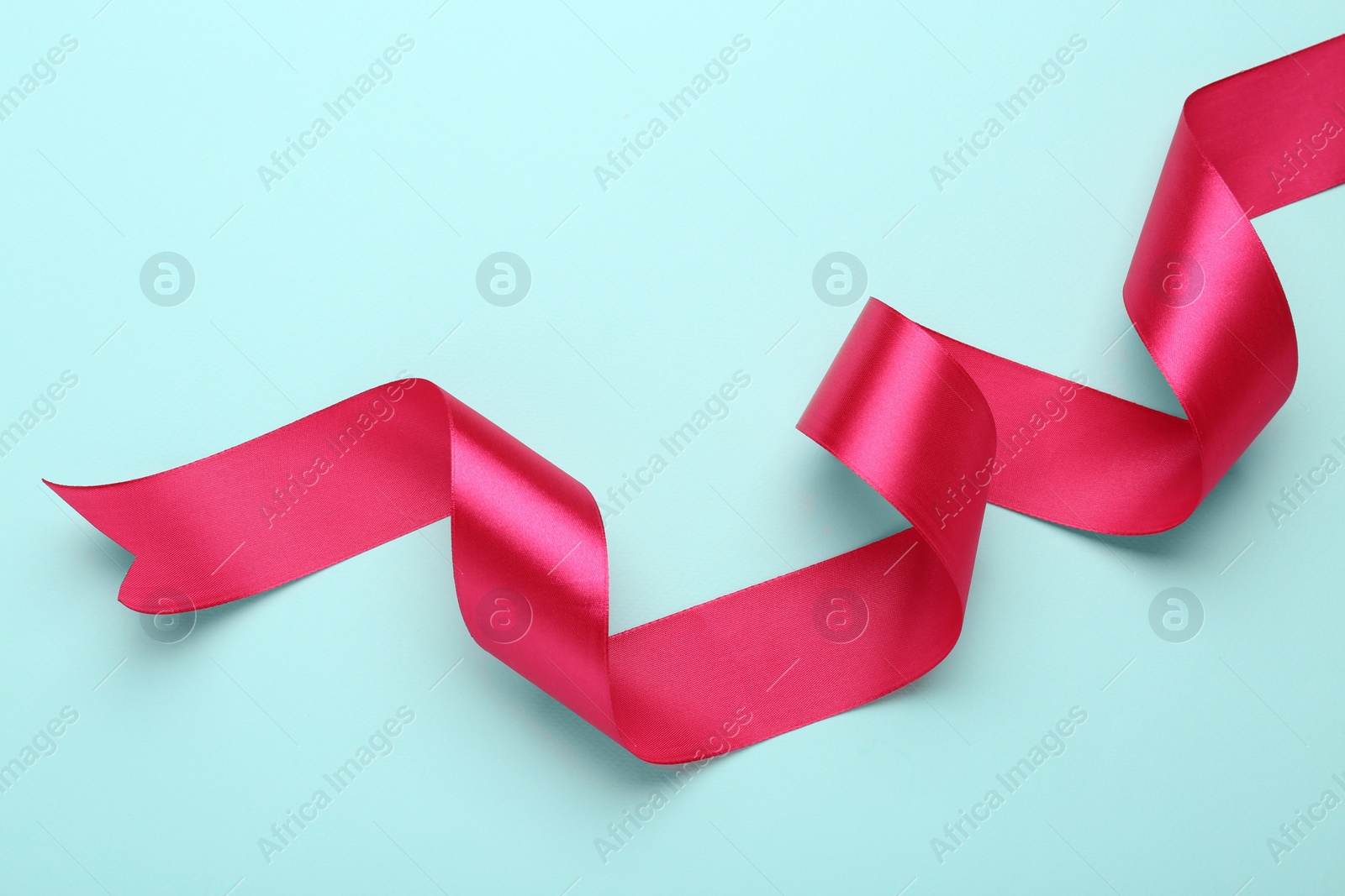 Photo of Beautiful pink ribbon on light blue background, top view