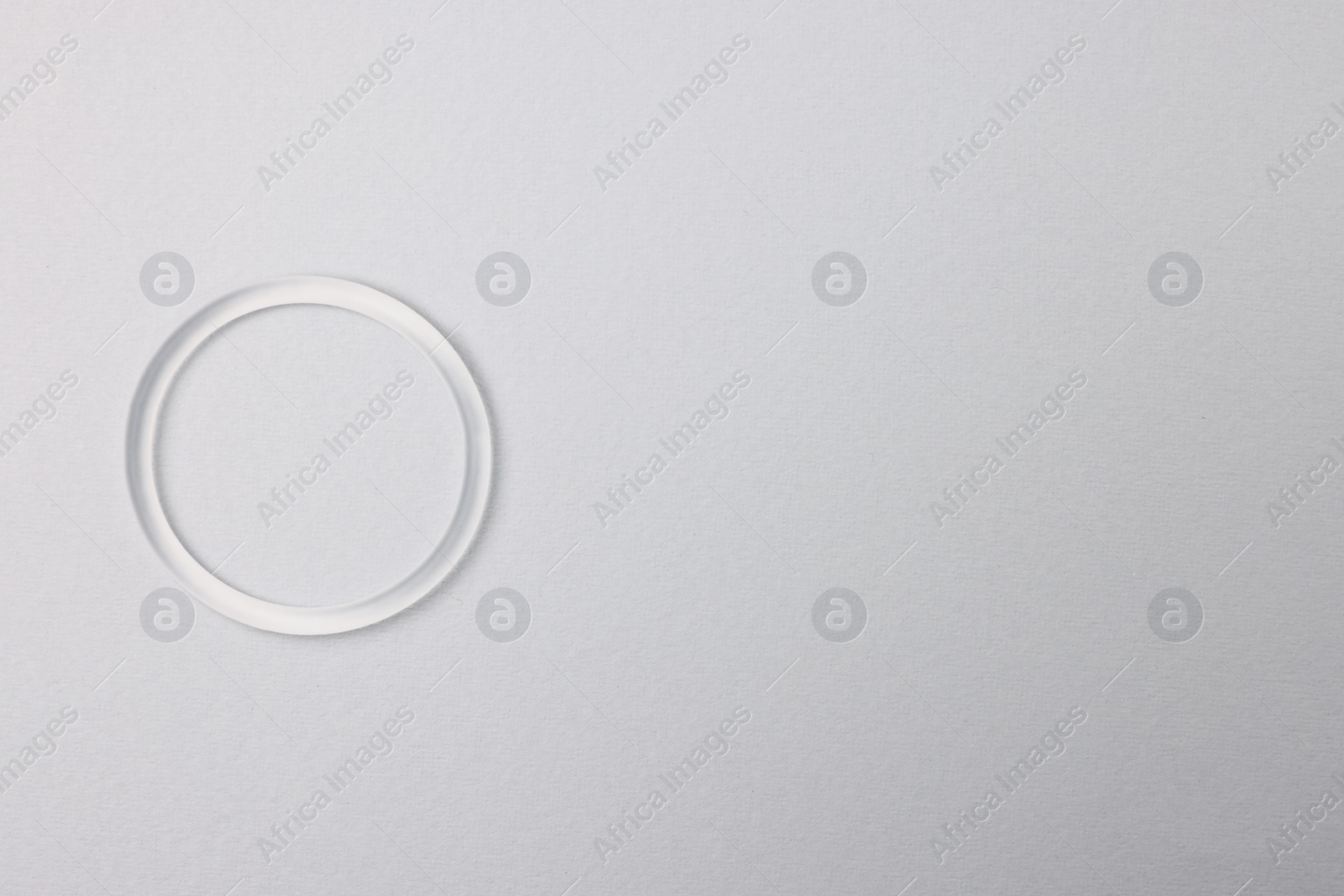 Photo of Diaphragm vaginal contraceptive ring on grey background, top view. Space for text