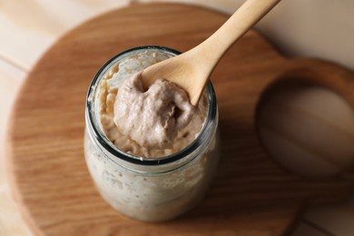 Photo of Taking sourdough starter with spoon at table, closeup