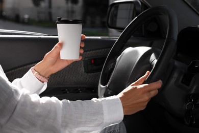 Photo of Coffee to go. Woman with paper cup of drink driving her car, closeup