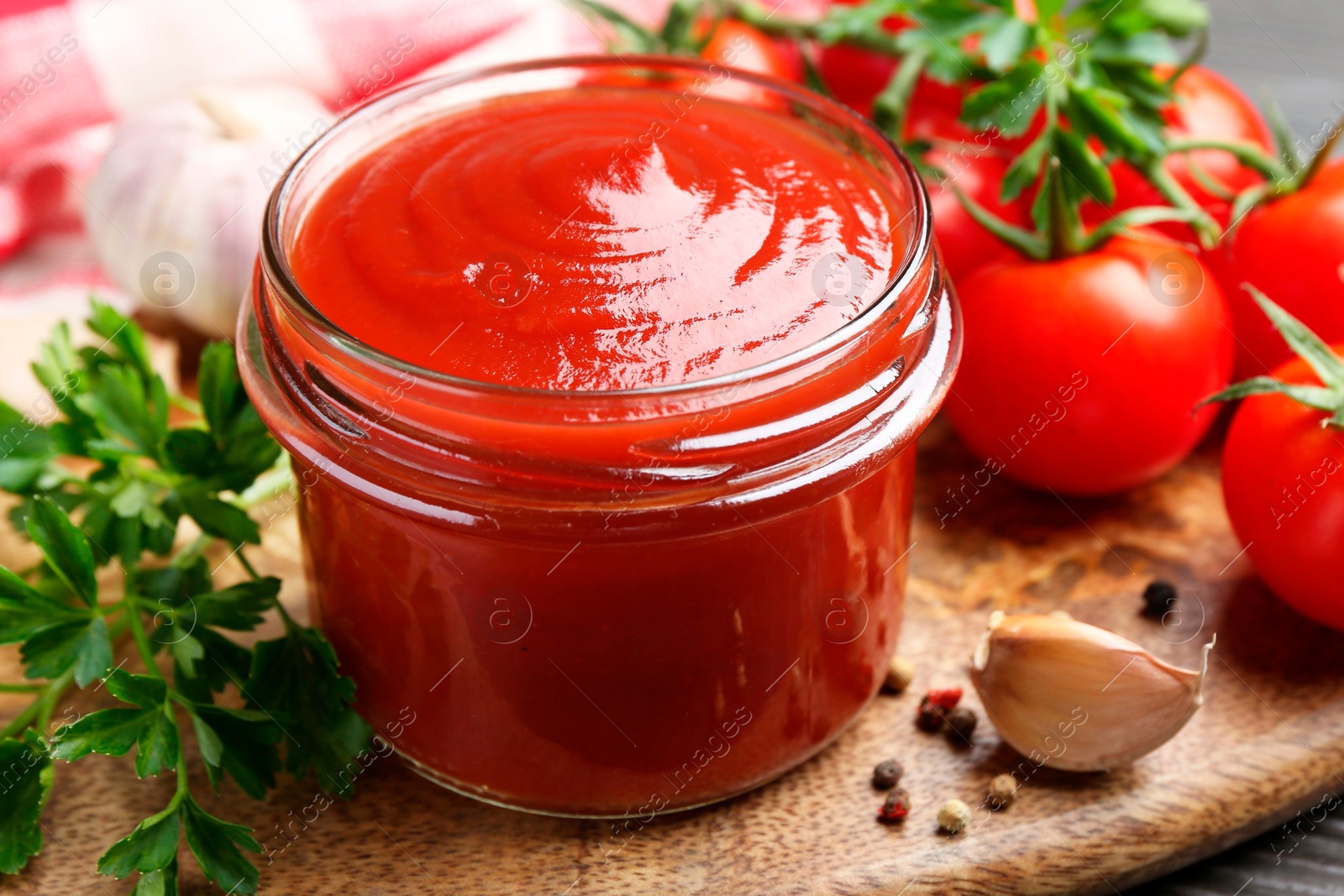 Photo of Tasty ketchup, fresh tomatoes, parsley and spices on grey wooden table