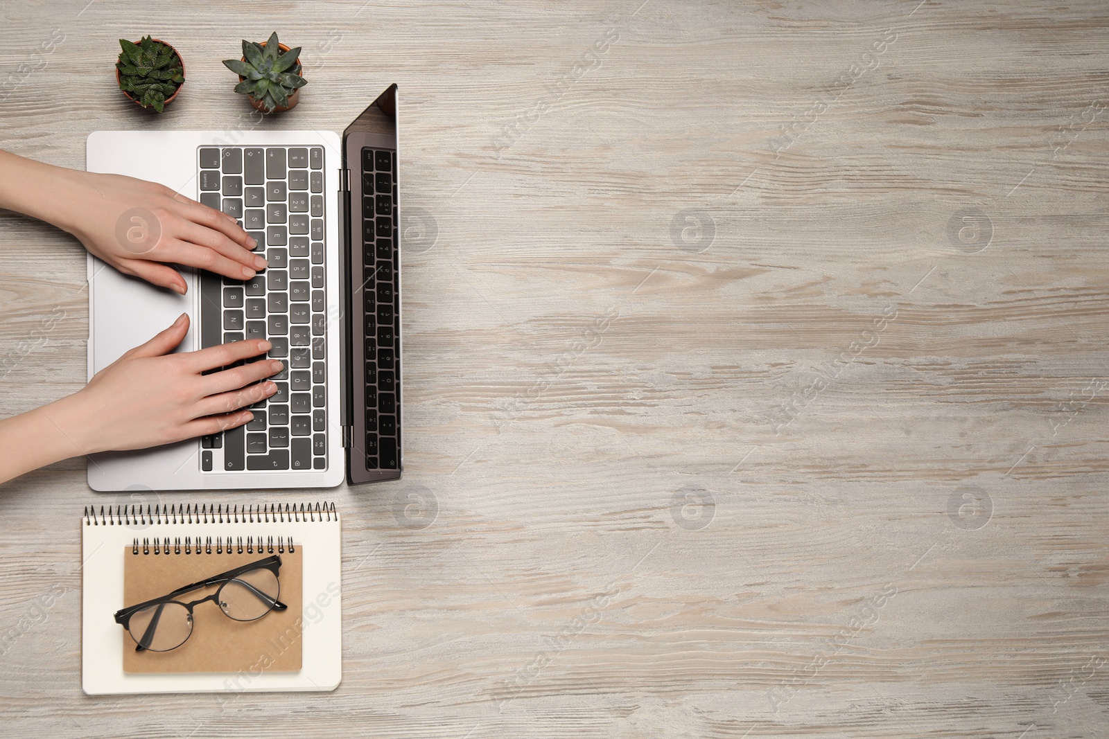 Photo of Woman using laptop at wooden table, top view. Space for text