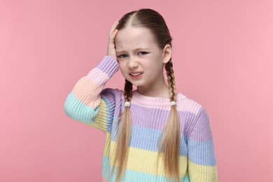 Little girl suffering from headache on pink background