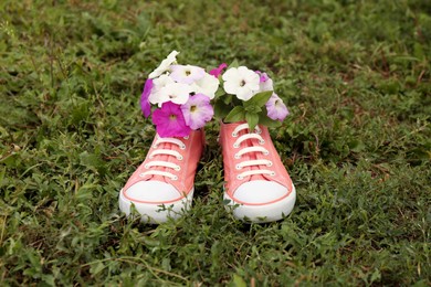 Photo of Shoes with beautiful flowers on grass outdoors