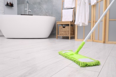 Cleaning dirty floor with mop in bathroom. Space for text