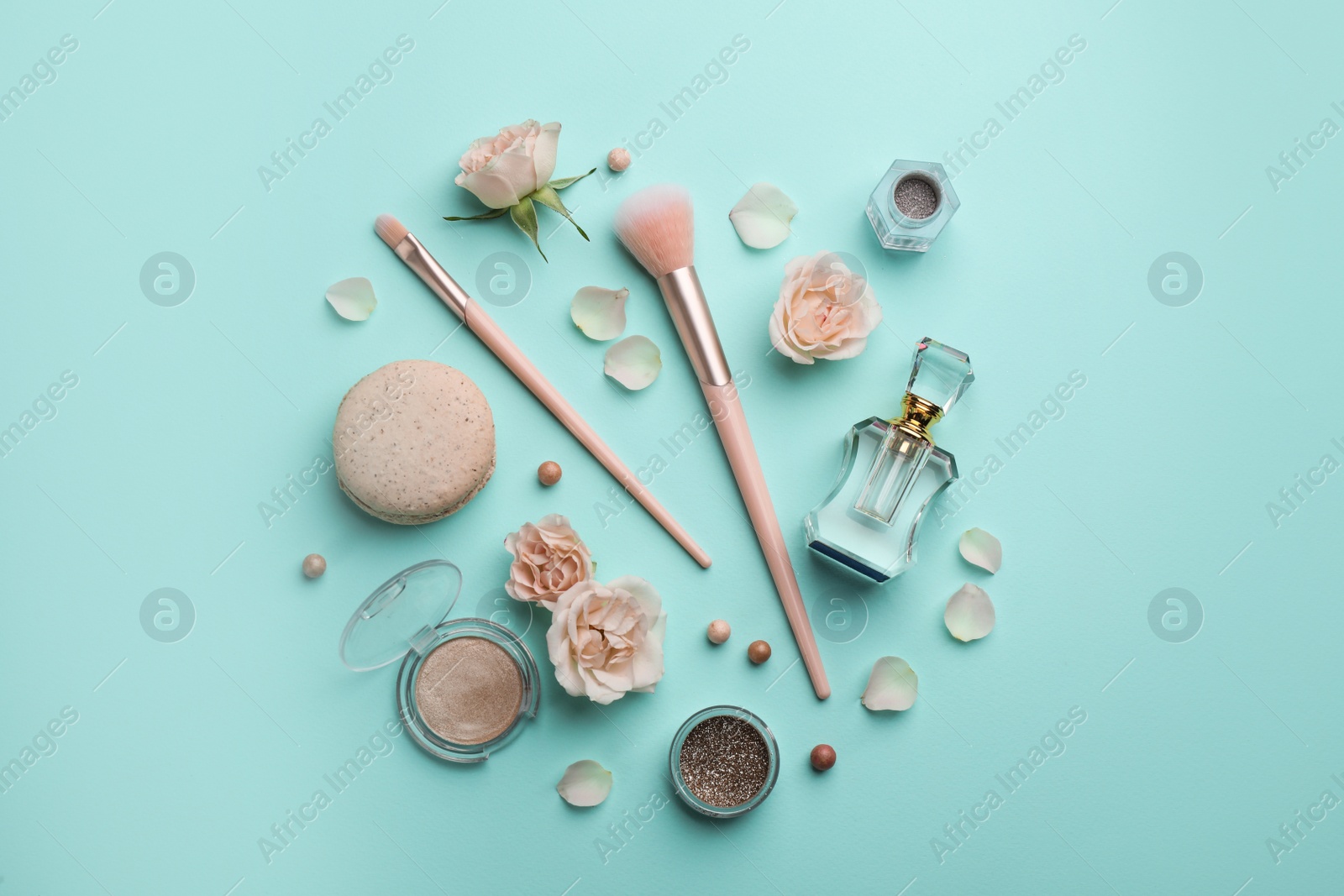 Photo of Flat lay composition with makeup products, roses and macaron on turquoise background