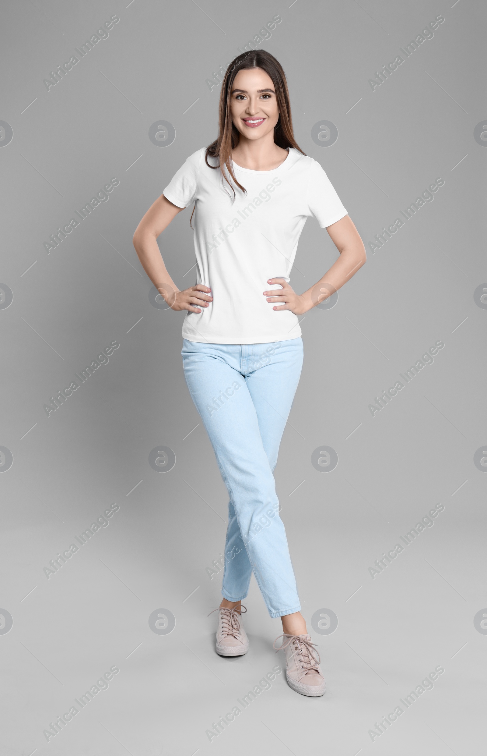 Photo of Young woman in stylish jeans on grey background