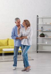 Photo of Happy senior couple dancing together in living room