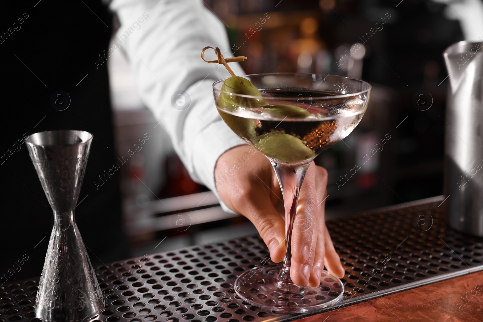 Photo of Bartender with fresh Martini cocktail at bar counter, closeup