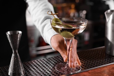 Photo of Bartender with fresh Martini cocktail at bar counter, closeup