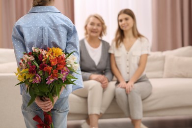 Photo of Little girl congratulating her mom and granny with flowers at home. Happy Mother's Day