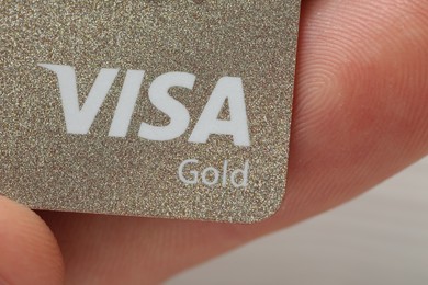 Photo of MYKOLAIV, UKRAINE - FEBRUARY 22, 2022: Woman holding Visa credit card on light background, closeup