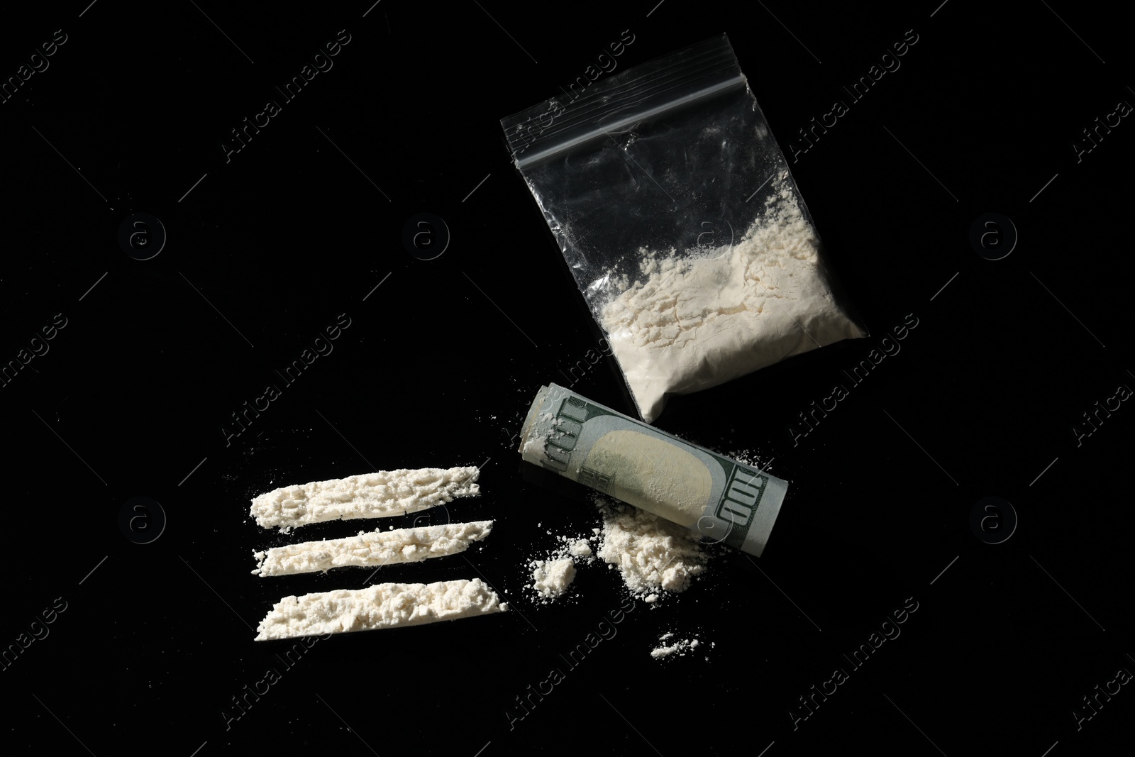 Photo of Drug addiction. Plastic bag with cocaine and rolled dollar banknote on black background,, flat lay