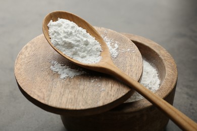 Photo of Baking powder in bowl and spoon on grey textured table