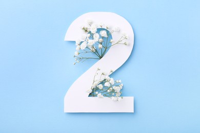 Paper number 2 and beautiful flowers on light blue background, top view