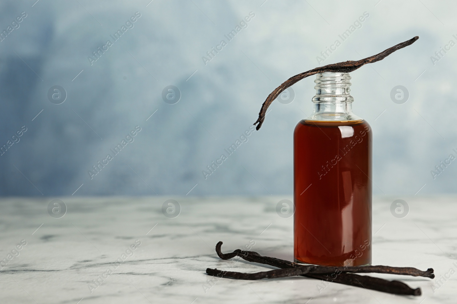 Photo of Aromatic homemade vanilla extract on marble table
