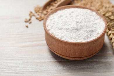 Photo of Bowl with wheat flour on wooden table, closeup. Space for text