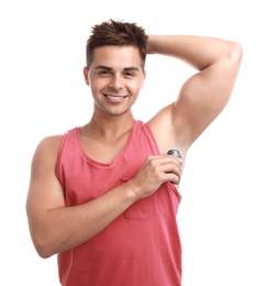 Young man applying deodorant to armpit on white background